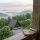 Notebook and brass telescope rest on a weathered wooden railing, overlooking a misty forested valley with cabins below in Highlands, NC.