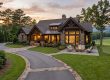 Luxurious stone-and-wood house with warm lighting, outdoor seating around a fire pit on a manicured lawn. Pre-arrival home prep