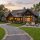 Luxurious stone-and-wood house with warm lighting, outdoor seating around a fire pit on a manicured lawn. Pre-arrival home prep