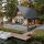 A-frame wooden cabin on a lakeside lot with a large deck, dock, and a boat beside calm water, surrounded by trees.