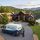Luxurious stone home on a hill overlooking a lake and forest, with a Property Stewards van in the driveway.