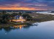 Charleston Coastal Homes with warm lights on a dock, reflections on calm water at sunset in a marshy inlet