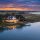 Charleston Coastal Homes with warm lights on a dock, reflections on calm water at sunset in a marshy inlet