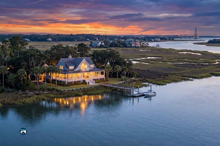 Charleston Coastal Homes with warm lights on a dock, reflections on calm water at sunset in a marshy inlet