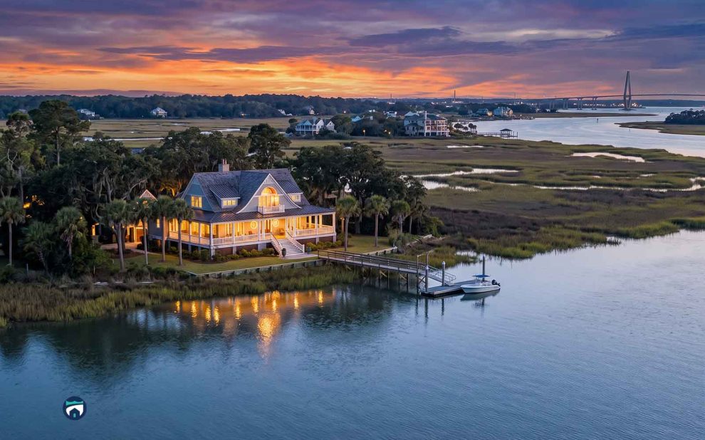 Charleston Coastal Homes with warm lights on a dock, reflections on calm water at sunset in a marshy inlet