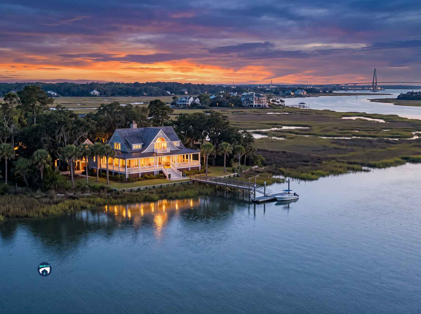 Fall-Coastal-Readiness-for-Charleston-Getaway-Homes-Storm-Follow-Up-for-the-Season-Ahead - Property Stewards Charleston Coastal Homes with warm lights on a dock, reflections on calm water at sunset in a marshy inlet