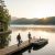 Stone cottage by a lake with a wooden dock; two men walk with fishing rods toward small boats at sunrise. Home Maintenance Concierge Services