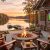 Lakeside patio at sunset with a stone fire pit, four wooden chairs draped in plaid blankets, and a TV showing a football game on the house wall overlooking a docked lake.
