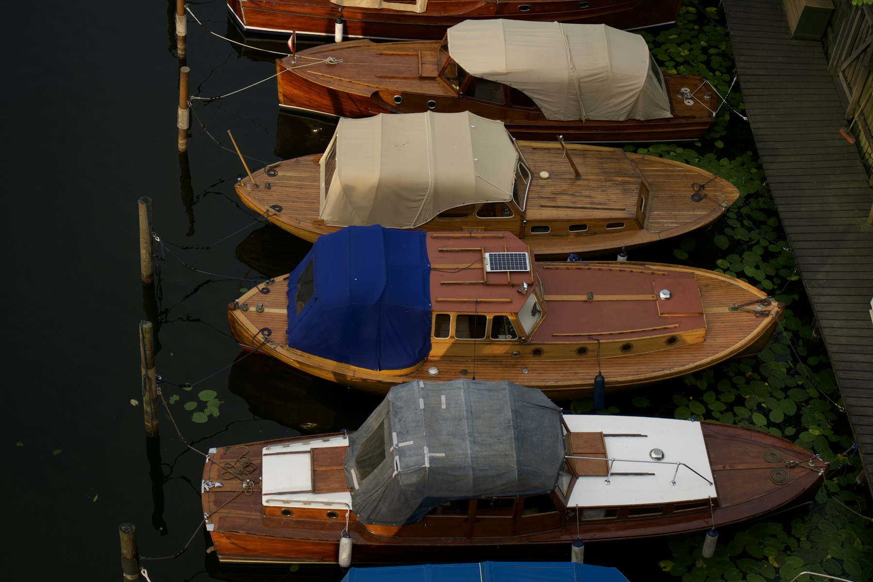 Boat Winterization and Covered Storage - Property Stewards Boats protected with canvas covers beside a wooden dock